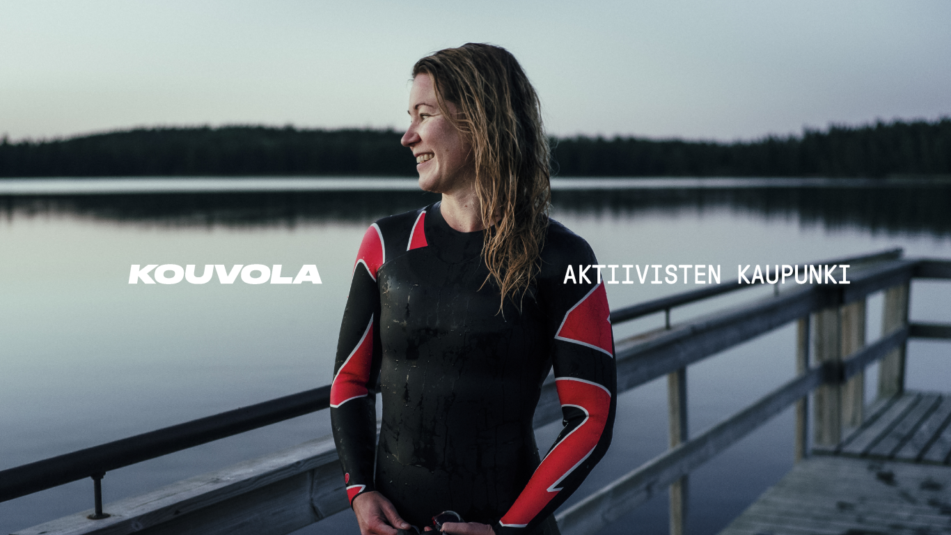 Logo: Kouvola. Slogan: Aktiivisten kaupunki. Hymyilevä nainen uimapuvussa, taustalla tyyni järvi.