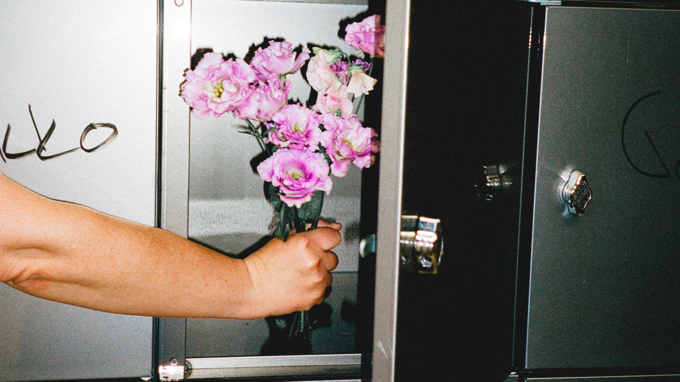 Käsi laittaa kukkia metalliseen lokeroon.